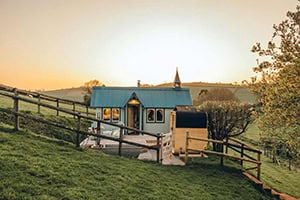Exterior of the Tabernacle at sunset showing the new wooden barrel sauna and turquoise roof.